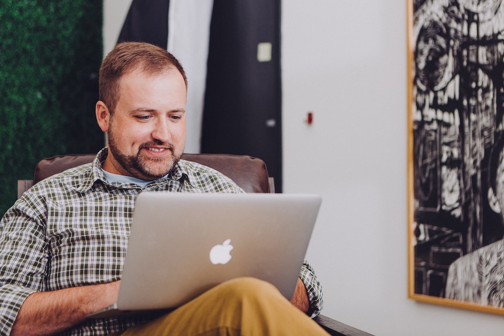 open APIs support growth. Man looking at laptop sitting in an office space.