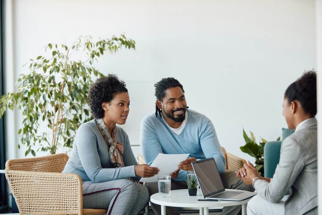 A couple smiles at their financial advisor during an office meeting.